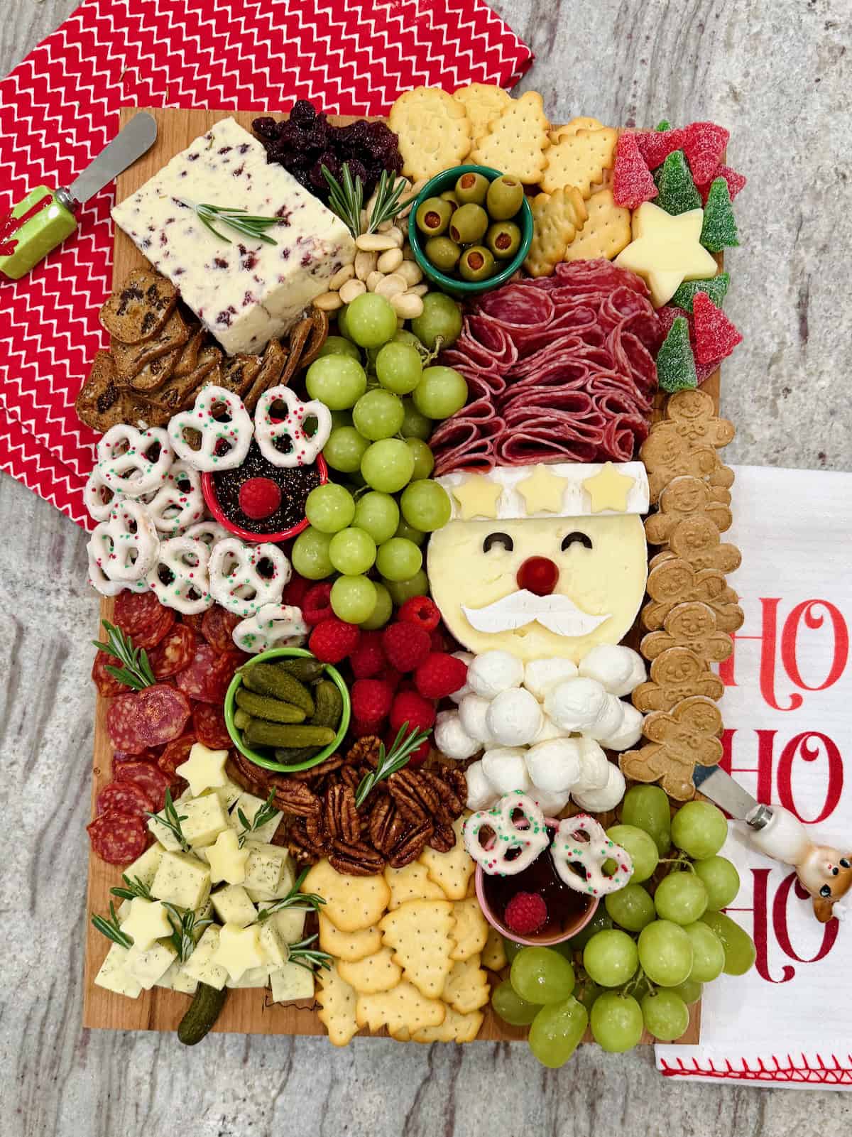 A Christmas charcuterie board with a Santa made out of salami and cheeses, as well as other festive touches.