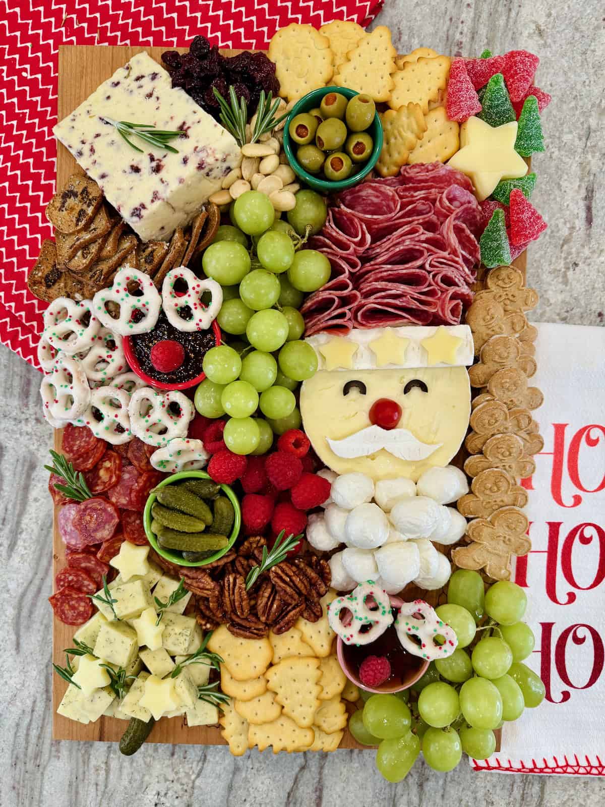 A Christmas charcuterie board with a Santa made out of salami and cheeses, as well as other festive touches.