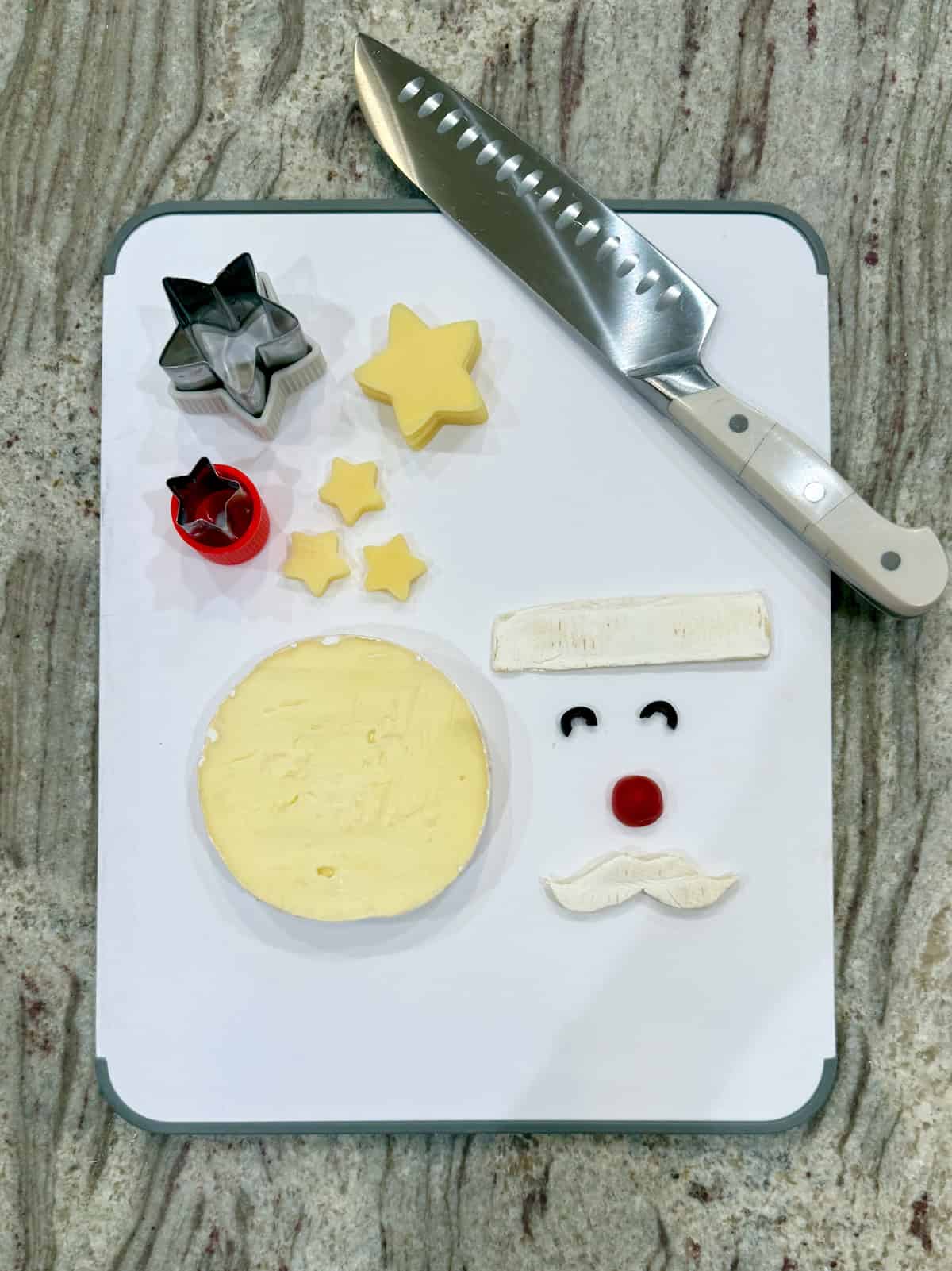 A cutting board with cheese cut outs for a charcuterie Santa.