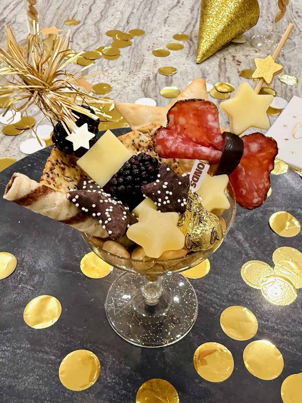 A champagne coupe filled with charcuterie snacks.