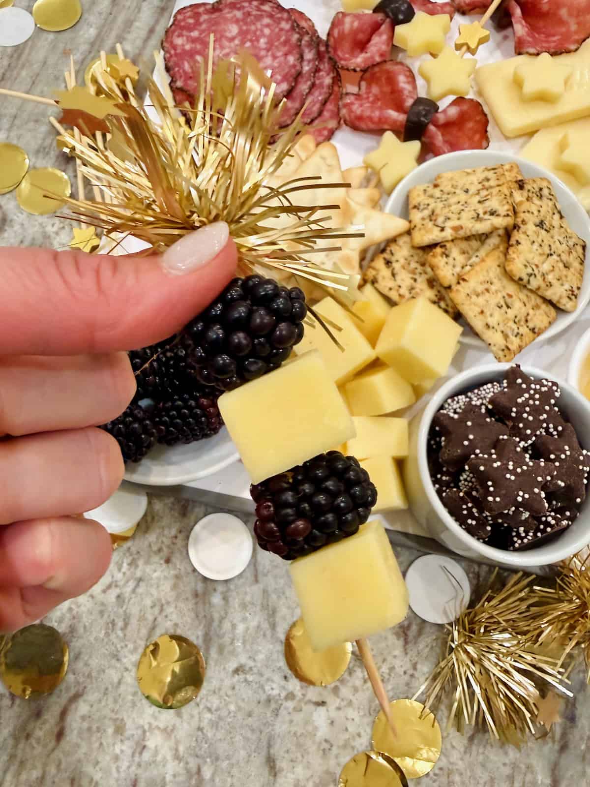 A skewer with blackberries and cubes of white cheese.