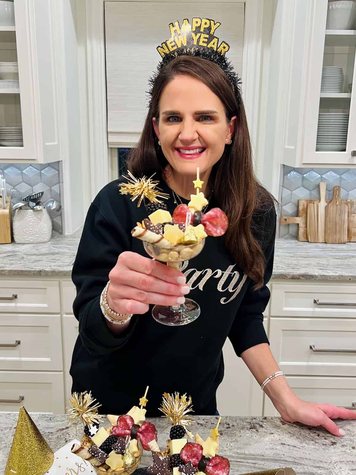 Maegan Brown holding a champagne coupe filled with charcuterie items.