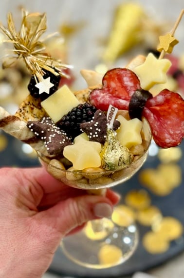 A champagne coupe filled with charcuterie snacks.