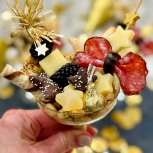 A champagne coupe filled with charcuterie snacks.