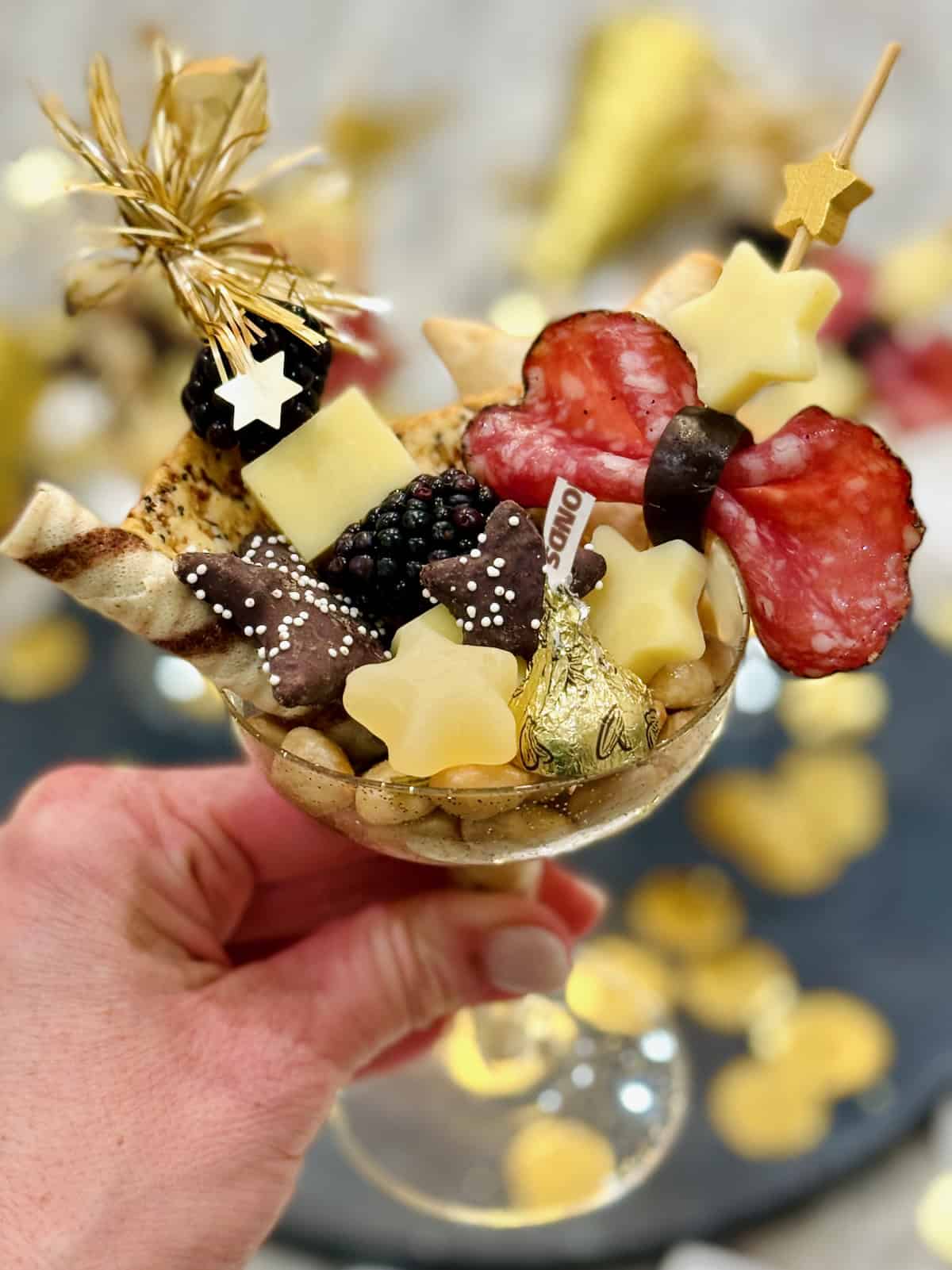 A champagne coupe filled with charcuterie snacks.