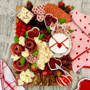 A wood food board decorated with Valentine's Day themed charcuterie items.