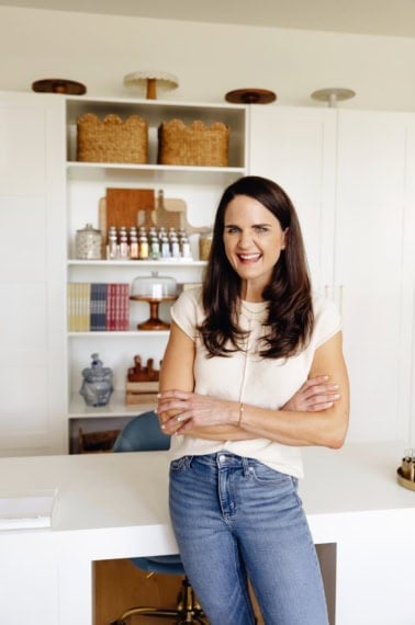 Maegan Brown wearing a white short sleeve top posing in front of her office cabinets.