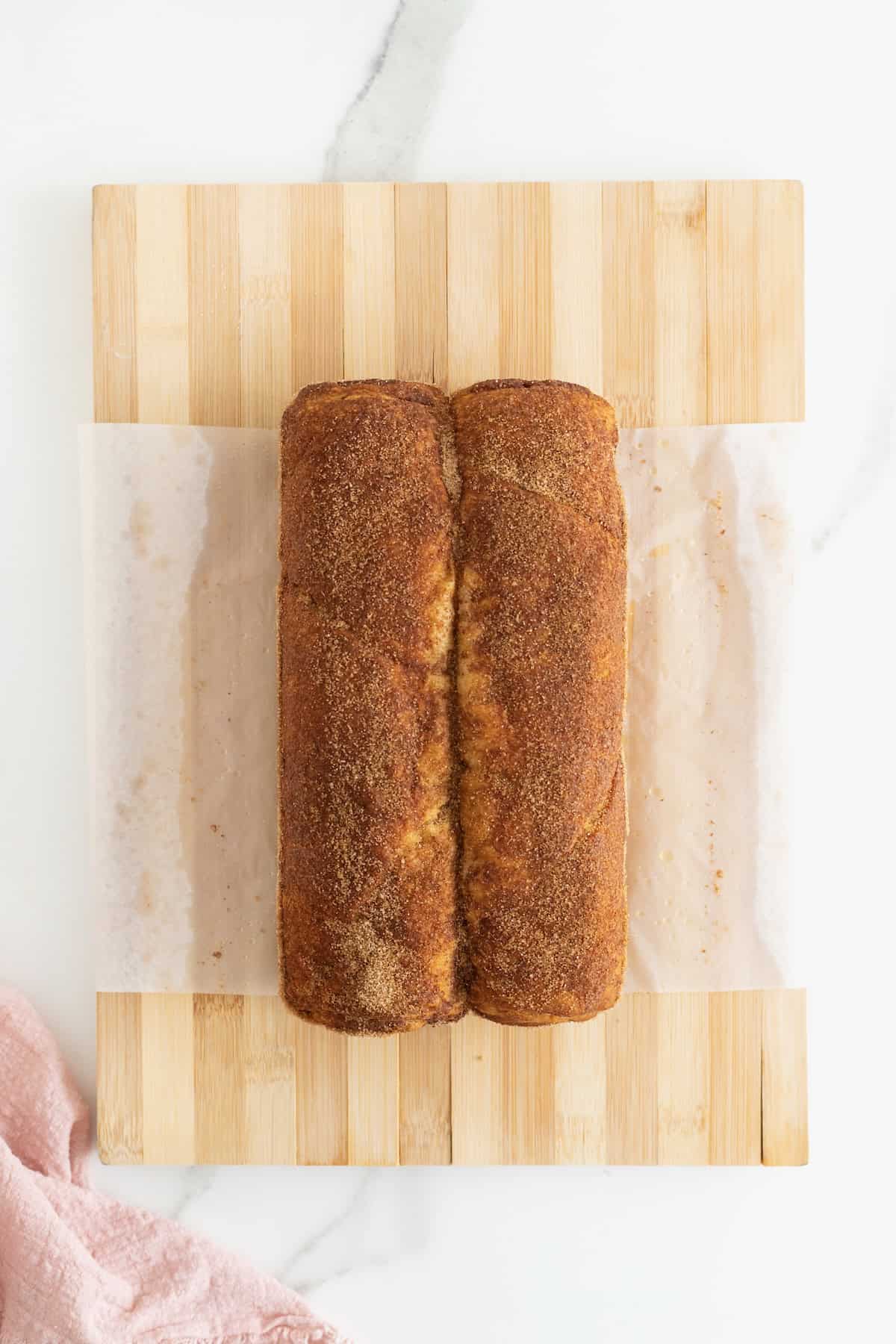 A cinnamon sugar crescent loaf on a parchment lined cutting board.