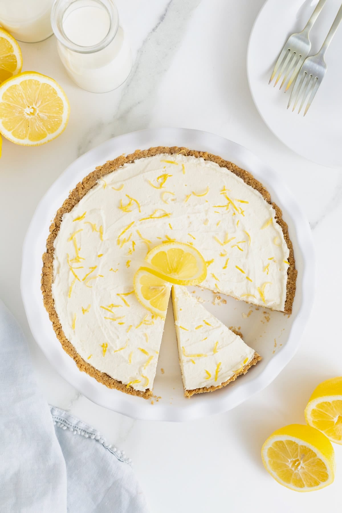 A frozen lemonade pie in a fluted white glass pie plate.