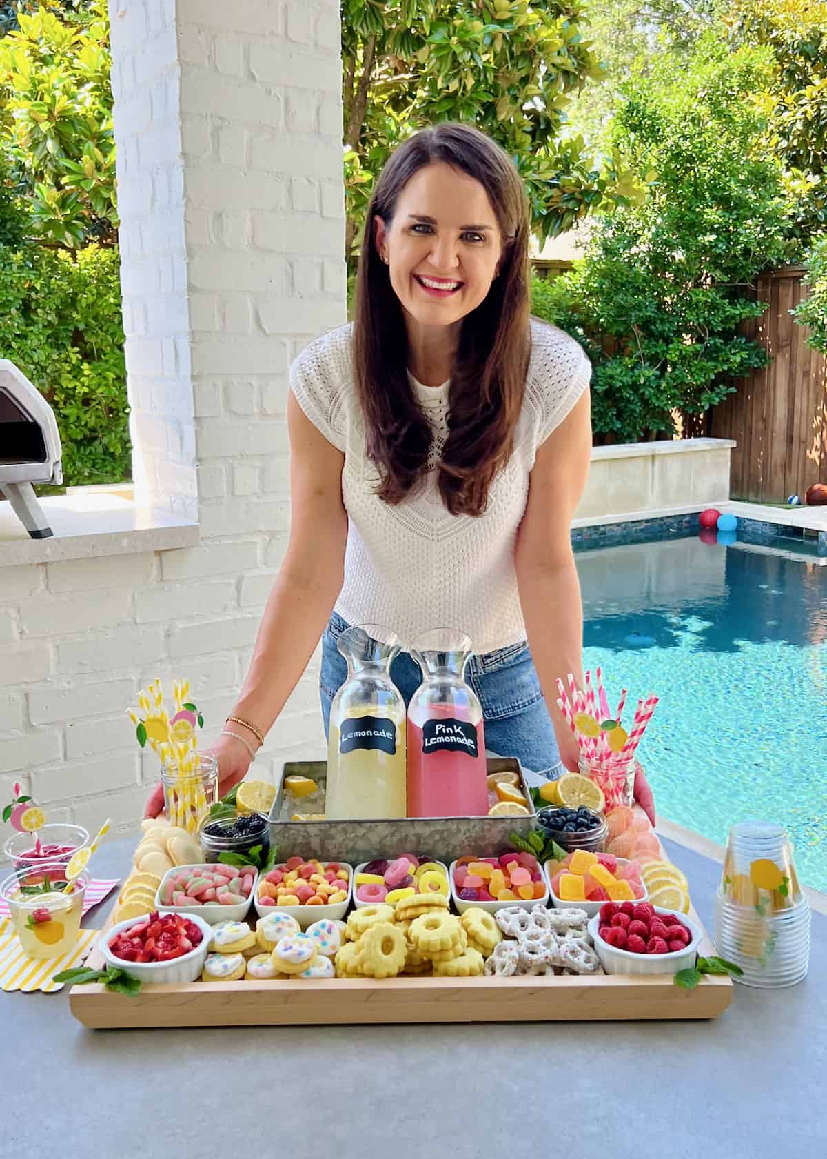 Maegan Brown wearing a white blouse. In front of her is a food board with candies, cookies and lemonade.