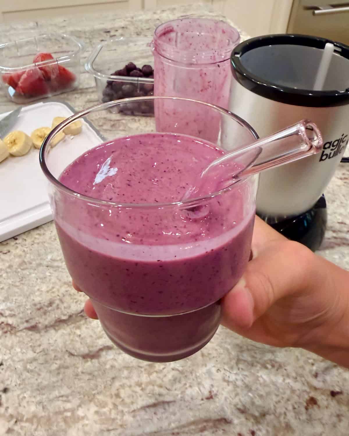 A berry smoothie in a tumbler with a straw.