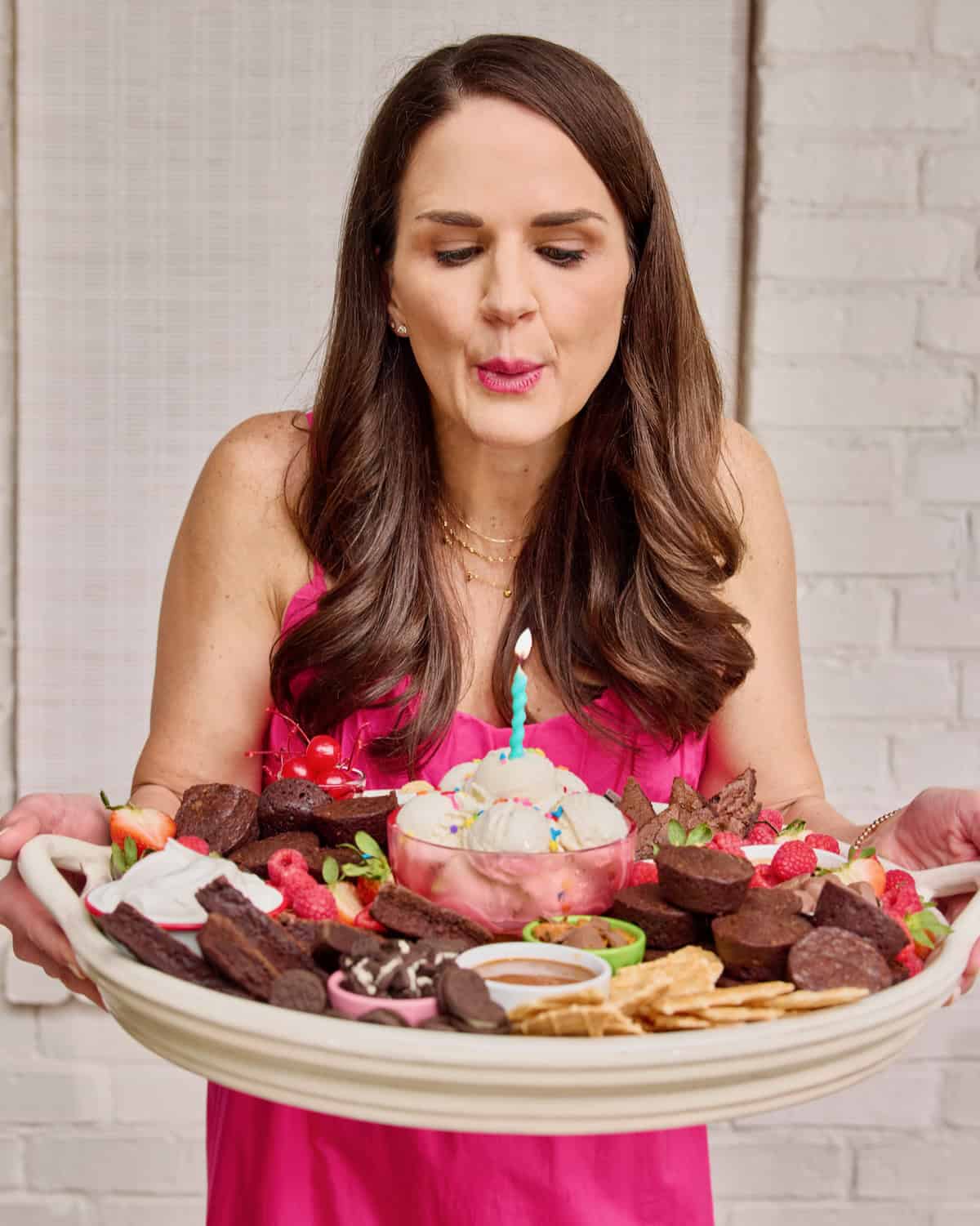 Maegan Brown wearing a pink sundress holding a brownie sundae board.