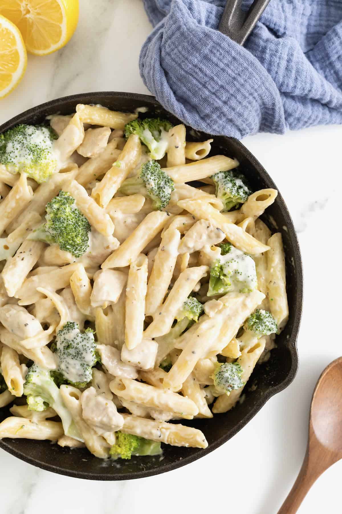 A cast iron skillet of ziti and broccoli covered in a cream sauce.