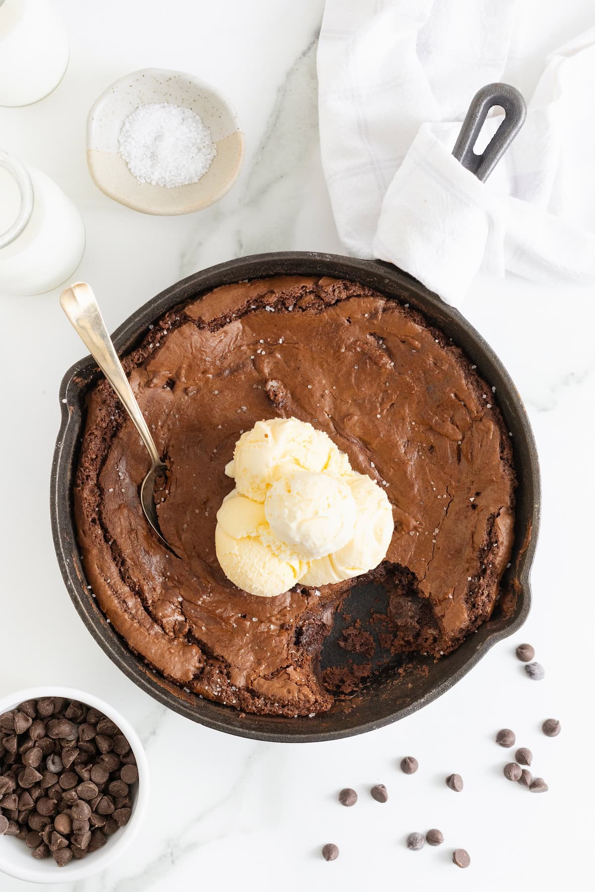A skillet brownie topped with several scoops of vanilla ice cream.