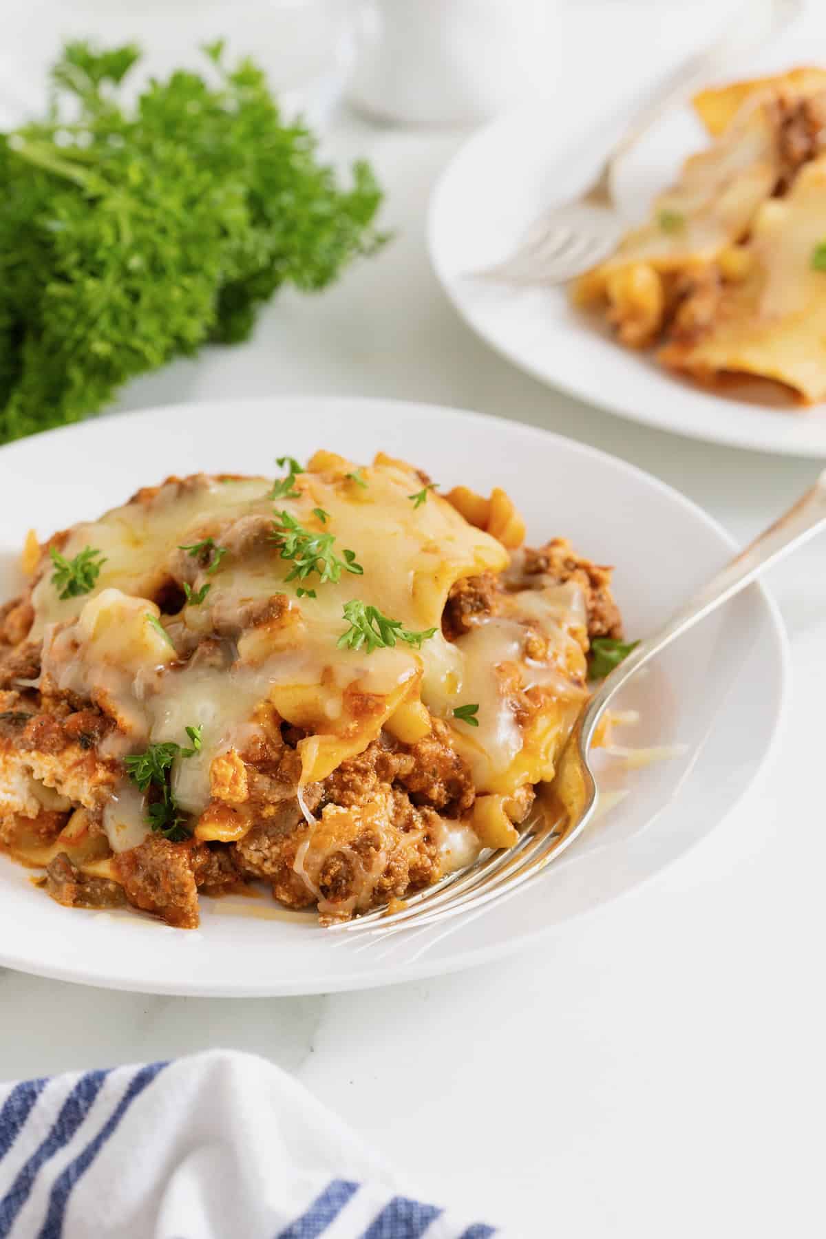A serving of skillet lasagna on a white dinner plate with a fork.