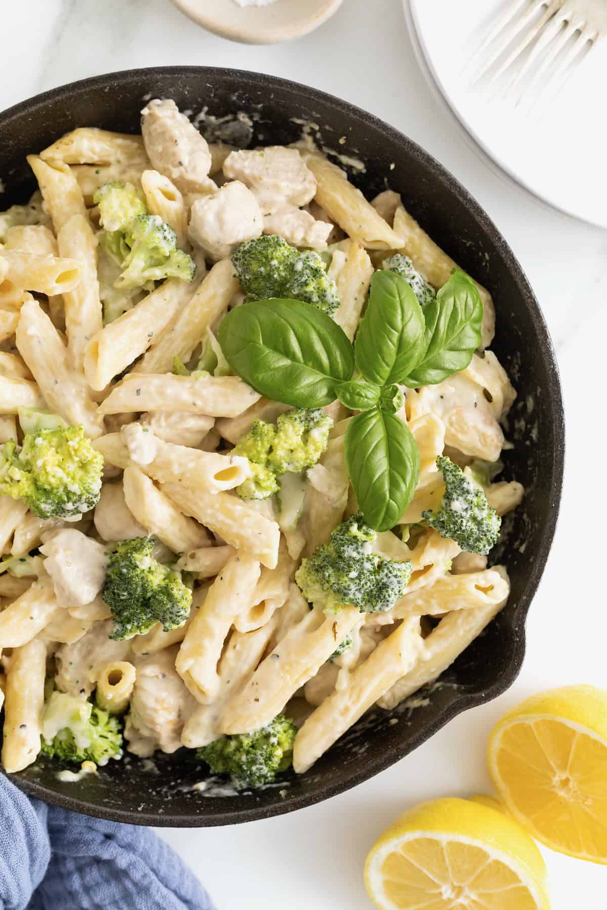 A cast iron skillet of ziti and broccoli covered in a cream sauce.