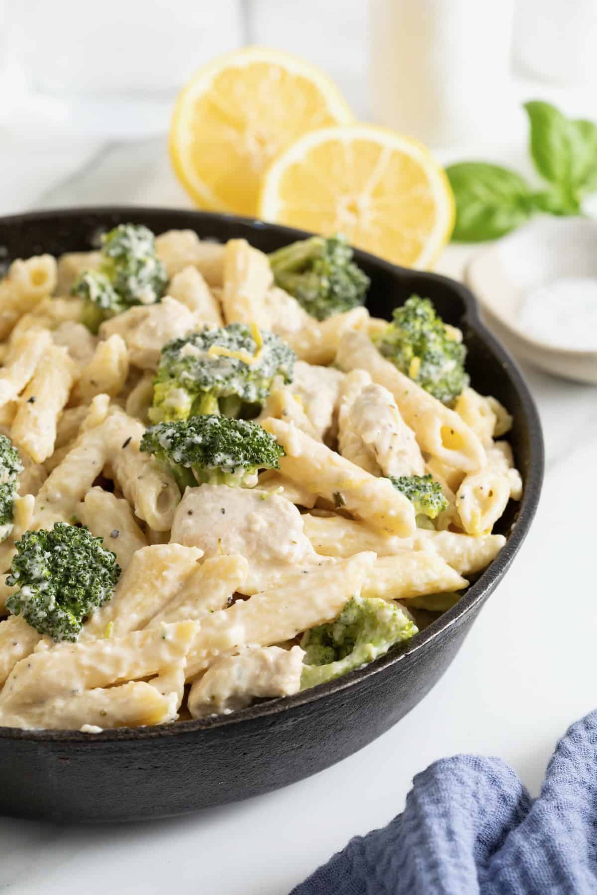 A cast iron skillet of ziti and broccoli covered in a cream sauce.