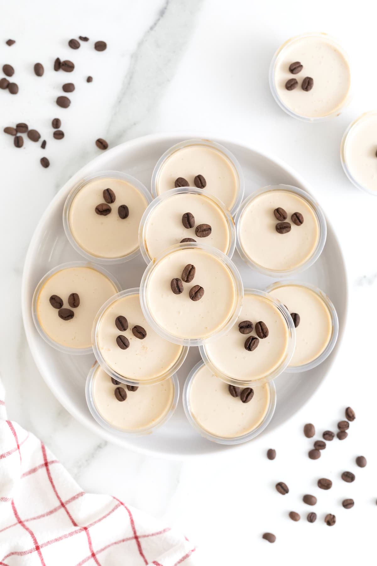 A white serving plate of espresso martini jello shots with lids on them.