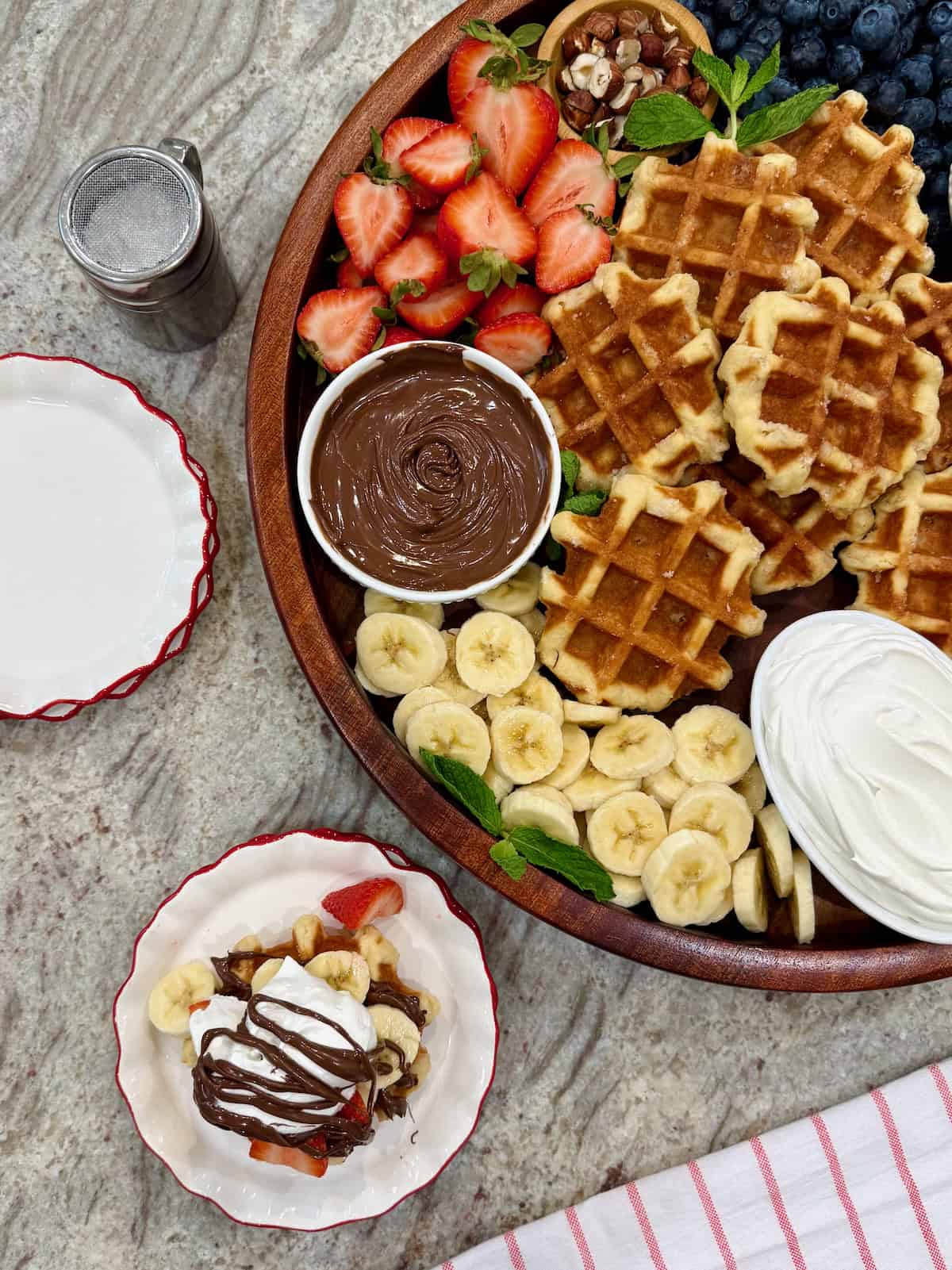 A large wooden round tray filled with liege-style waffles and toppings.