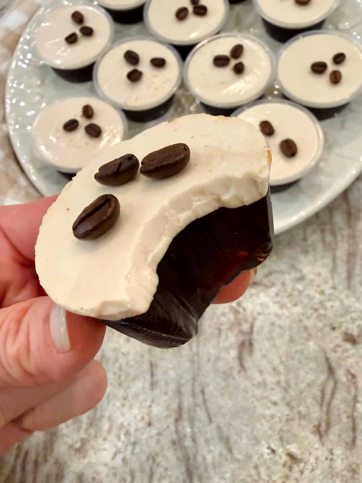 A hand holding an espresso martini shot with a bite out of it.