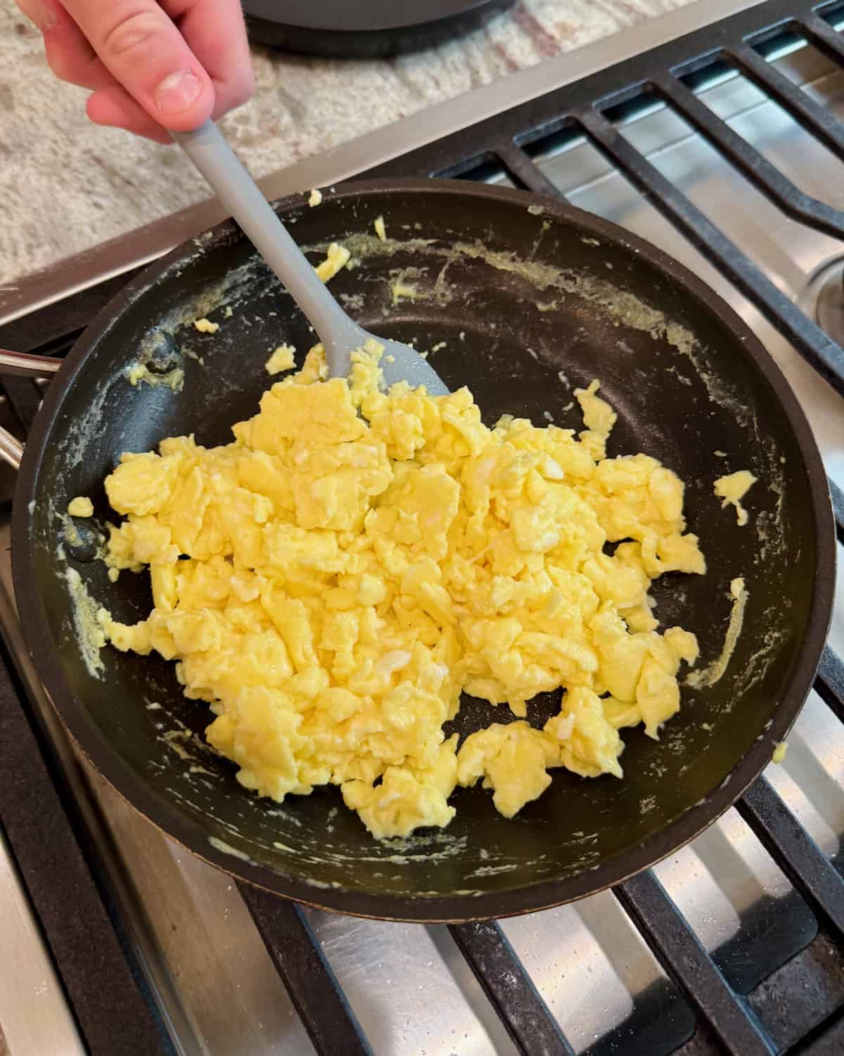 A dark skillet of soft scrambled eggs.