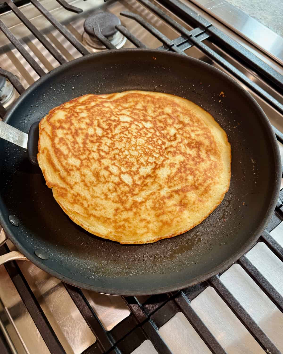 A single pancake in a dark skillet.