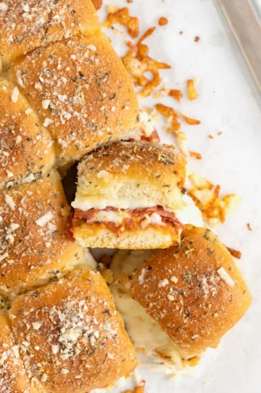 A pile of pizza sliders on an aluminum baking sheet.