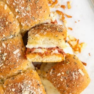A pile of pizza sliders on an aluminum baking sheet.
