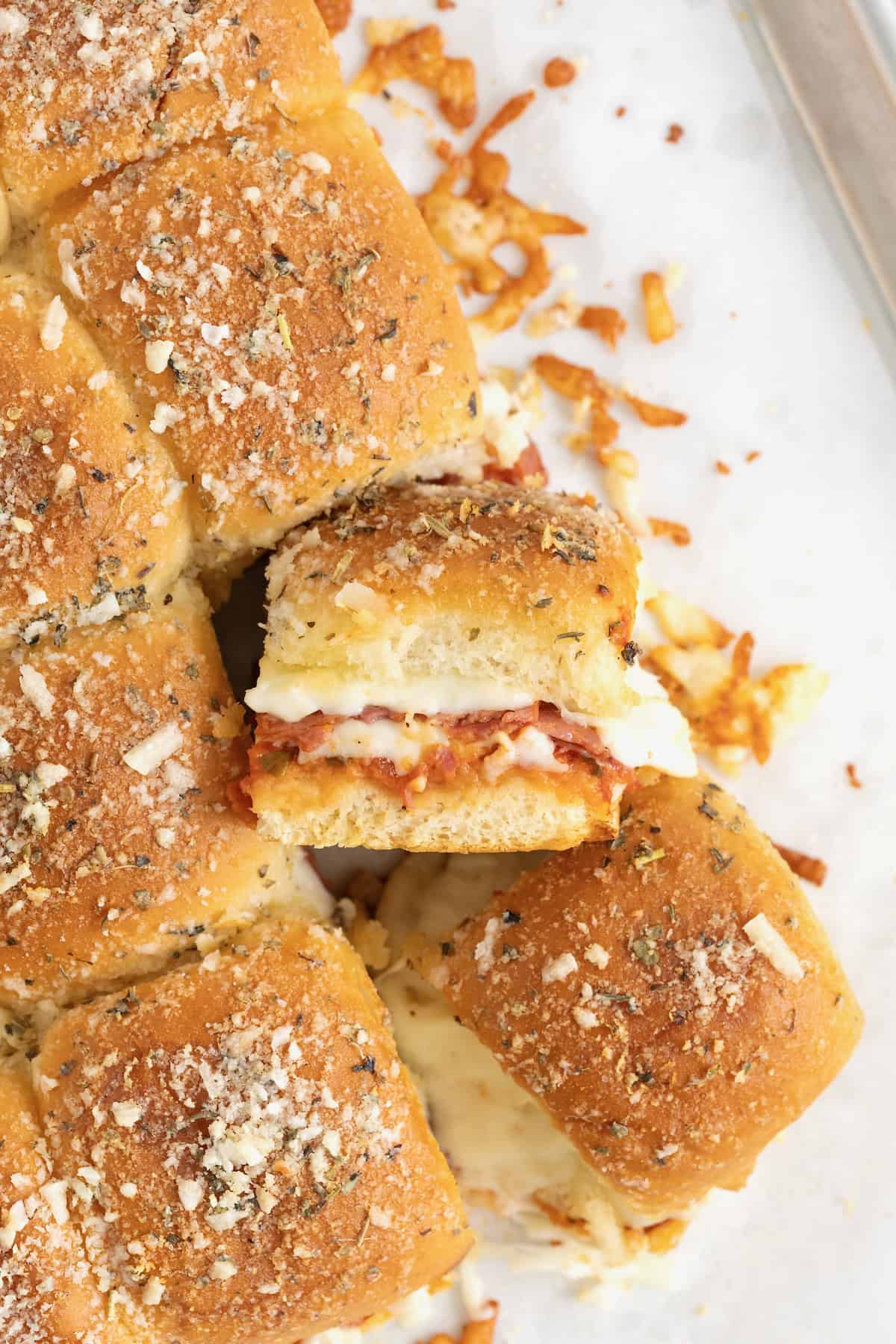 A pile of pizza sliders on an aluminum baking sheet.