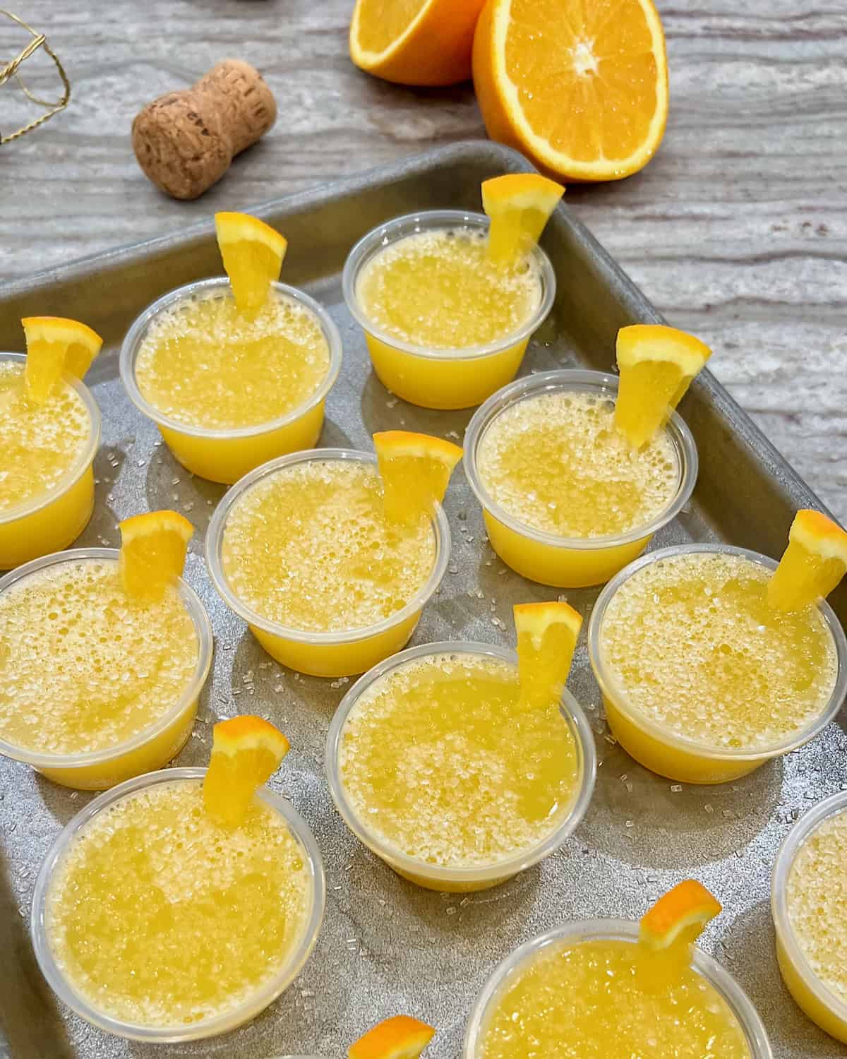 A rimmed aluminum baking sheet filled with mimosa jello shots.