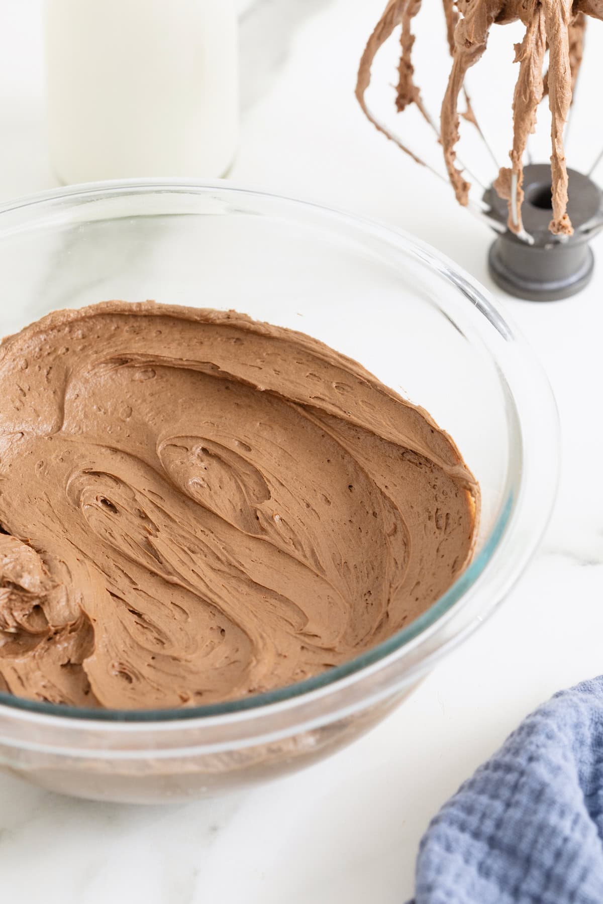 A glass mixing bowl of chocolate buttercream frosting.