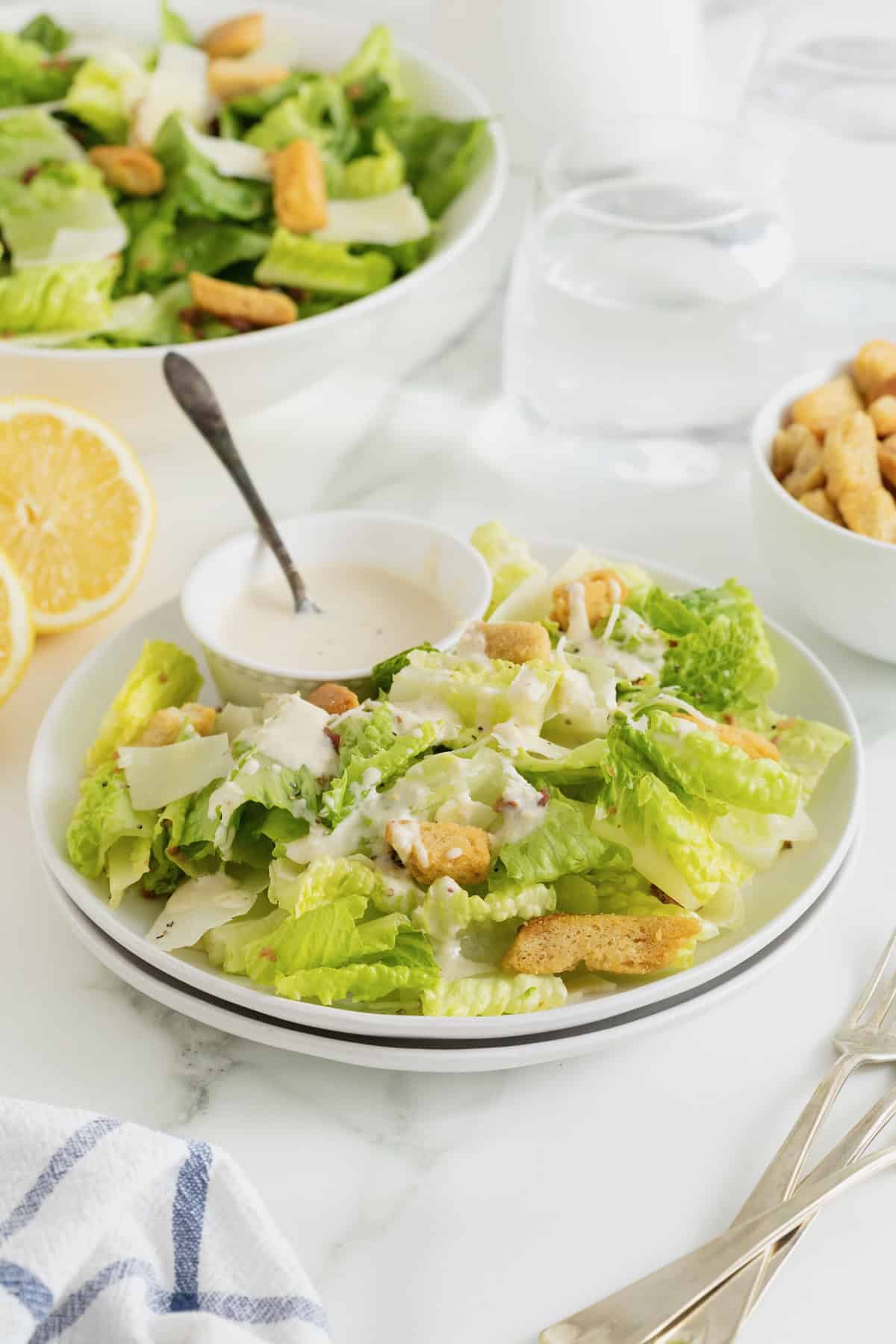A dinner plate of Caesar salad with a small white dish of Caesar dressing.