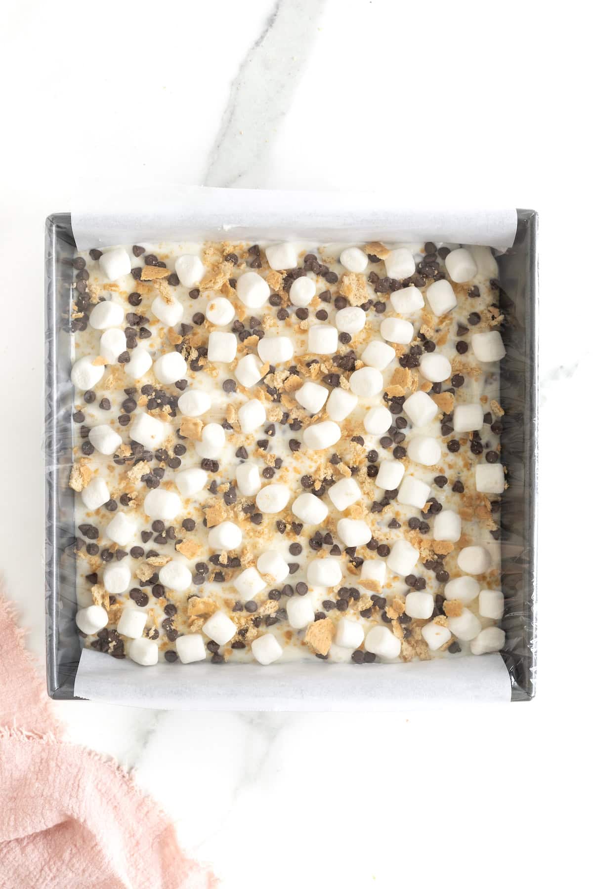 Plastic wrap over frozen yogurt bars in a square metal baking dish.