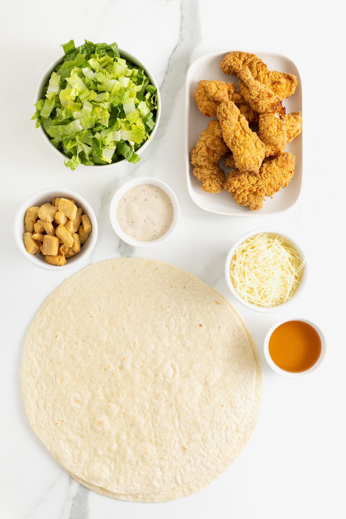Ingredients to make crispy hot honey chicken caesar wraps.