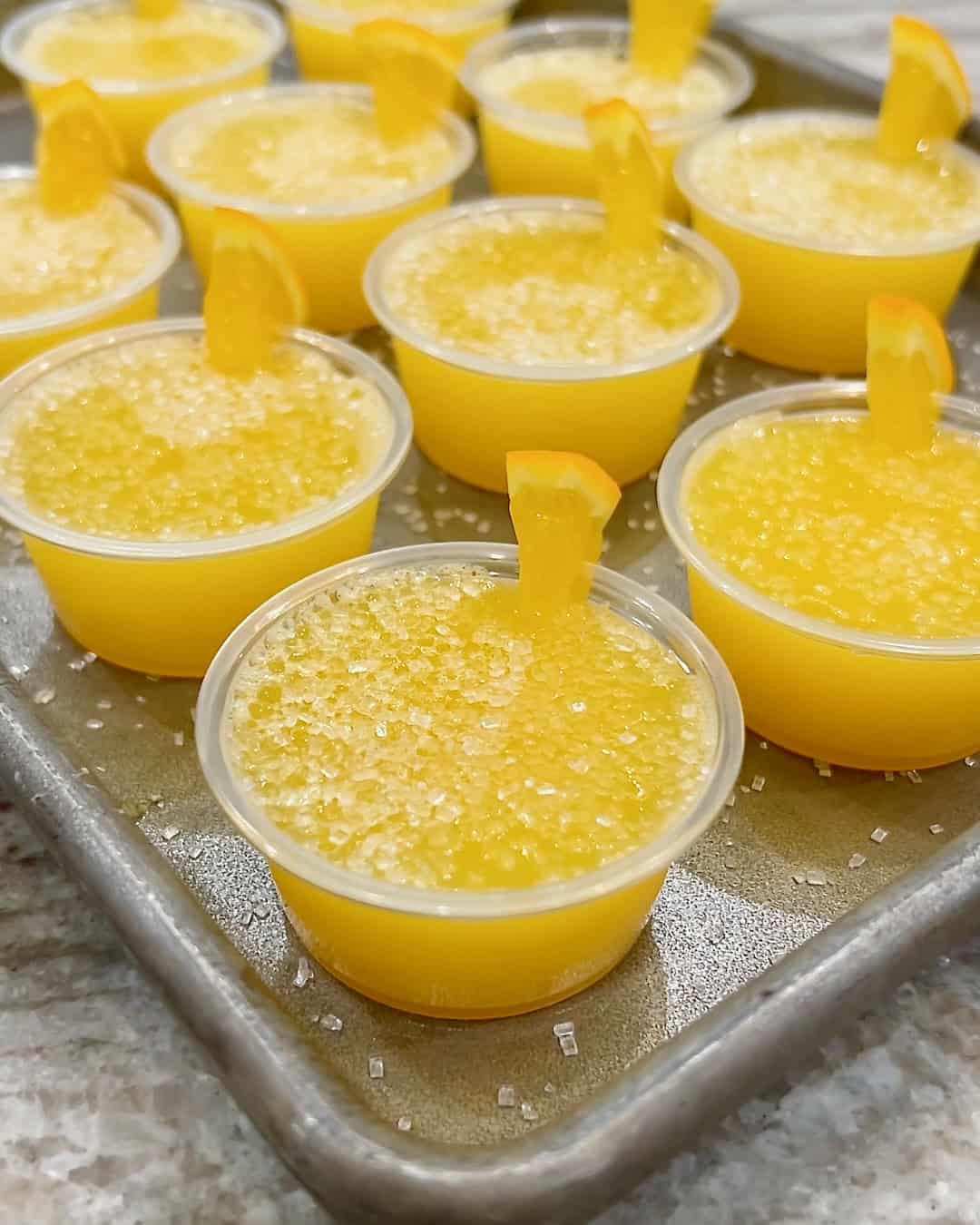 A rimmed aluminum baking sheet filled with mimosa jello shots.