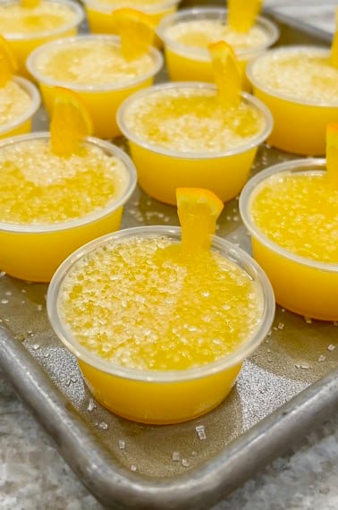 A rimmed aluminum baking sheet filled with mimosa jello shots.