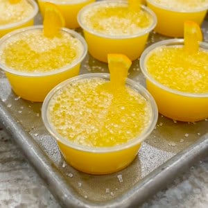 A rimmed aluminum baking sheet filled with mimosa jello shots.