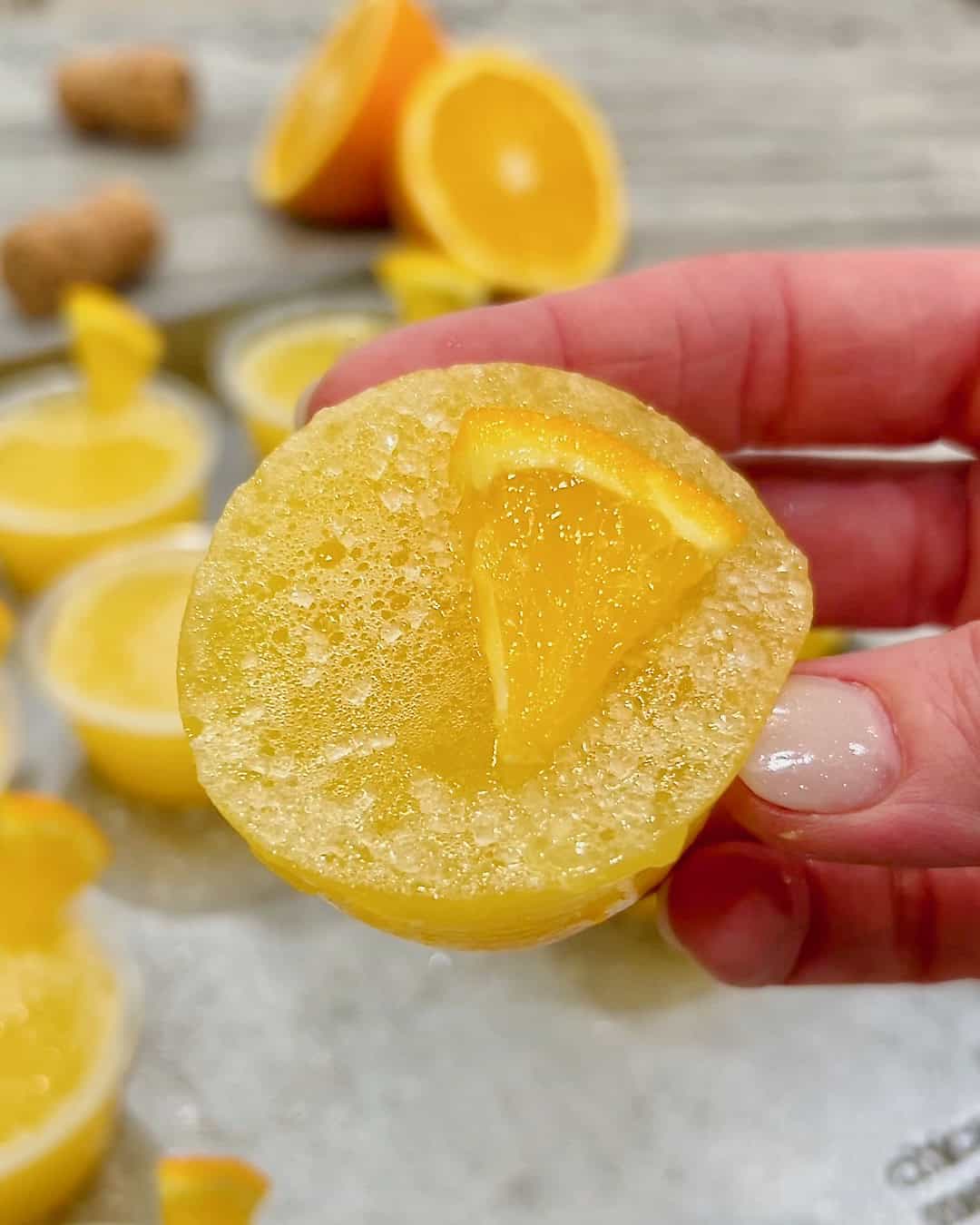 A hand holding a mimosa jello shot.