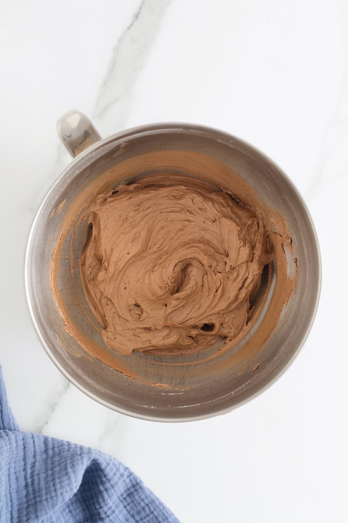 Chocolate buttercream frosting in a stainless mixing bowl.