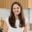 Maegan Brown smiling while seated in a bright, modern kitchen.