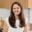 Maegan Brown smiling while seated in a bright, modern kitchen.