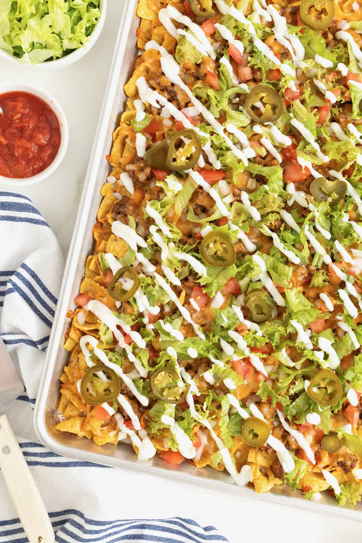 Sheet pan walking tacos drizzled with sour cream.