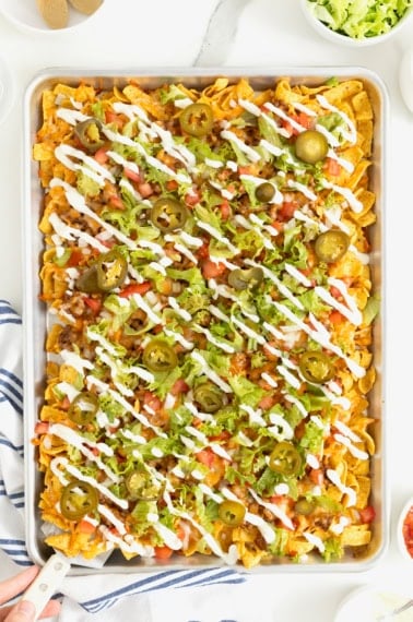 Sheet pan walking tacos drizzled with sour cream.