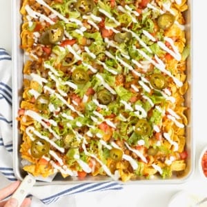 Sheet pan walking tacos drizzled with sour cream.