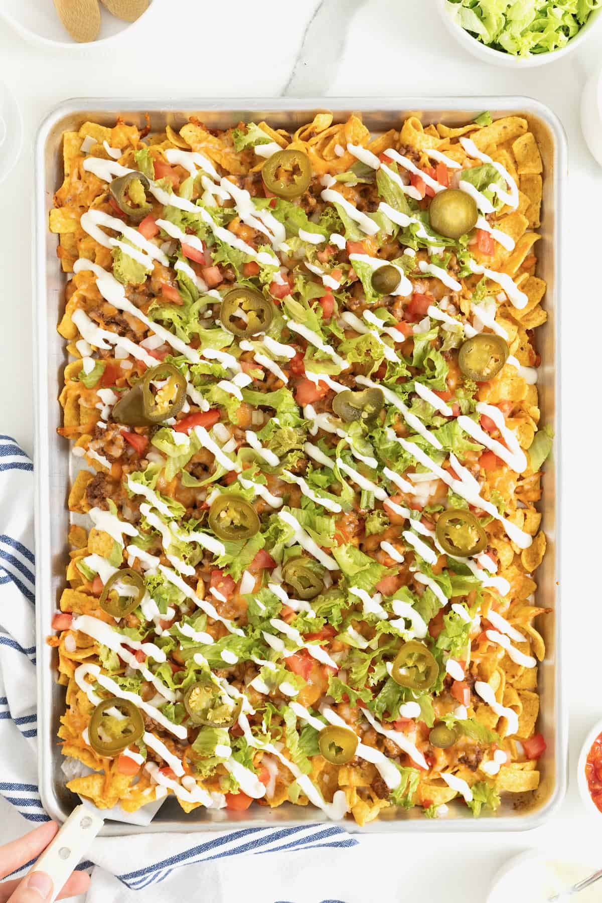 Sheet pan walking tacos drizzled with sour cream.