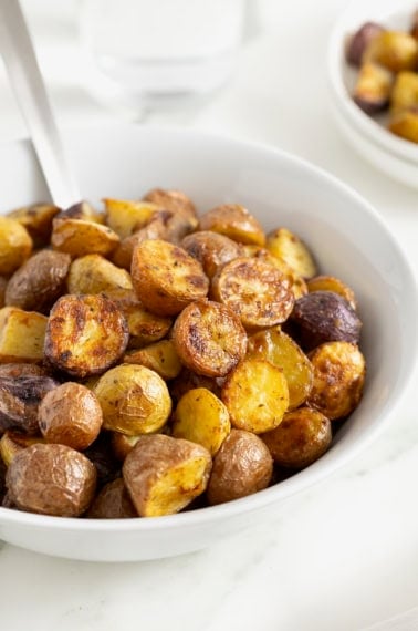 A white serving bowl of crispy potatoes seasoned with ranch.