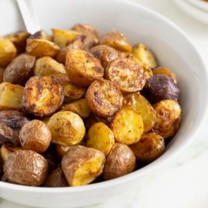 A white serving bowl of crispy potatoes seasoned with ranch.