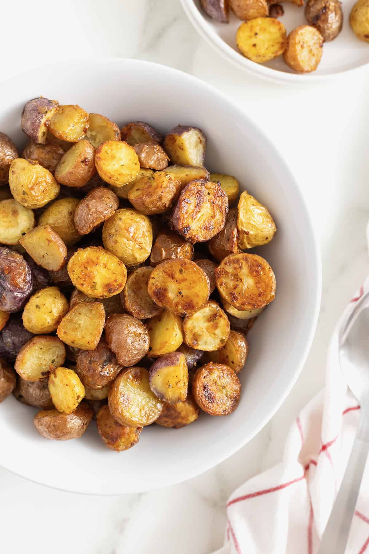 A white serving bowl of crispy potatoes seasoned with ranch.