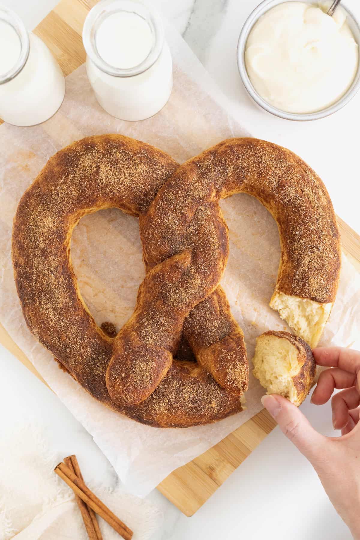 A jumbo soft pretzel covered in cinnamon sugar with a bite taken out of it.