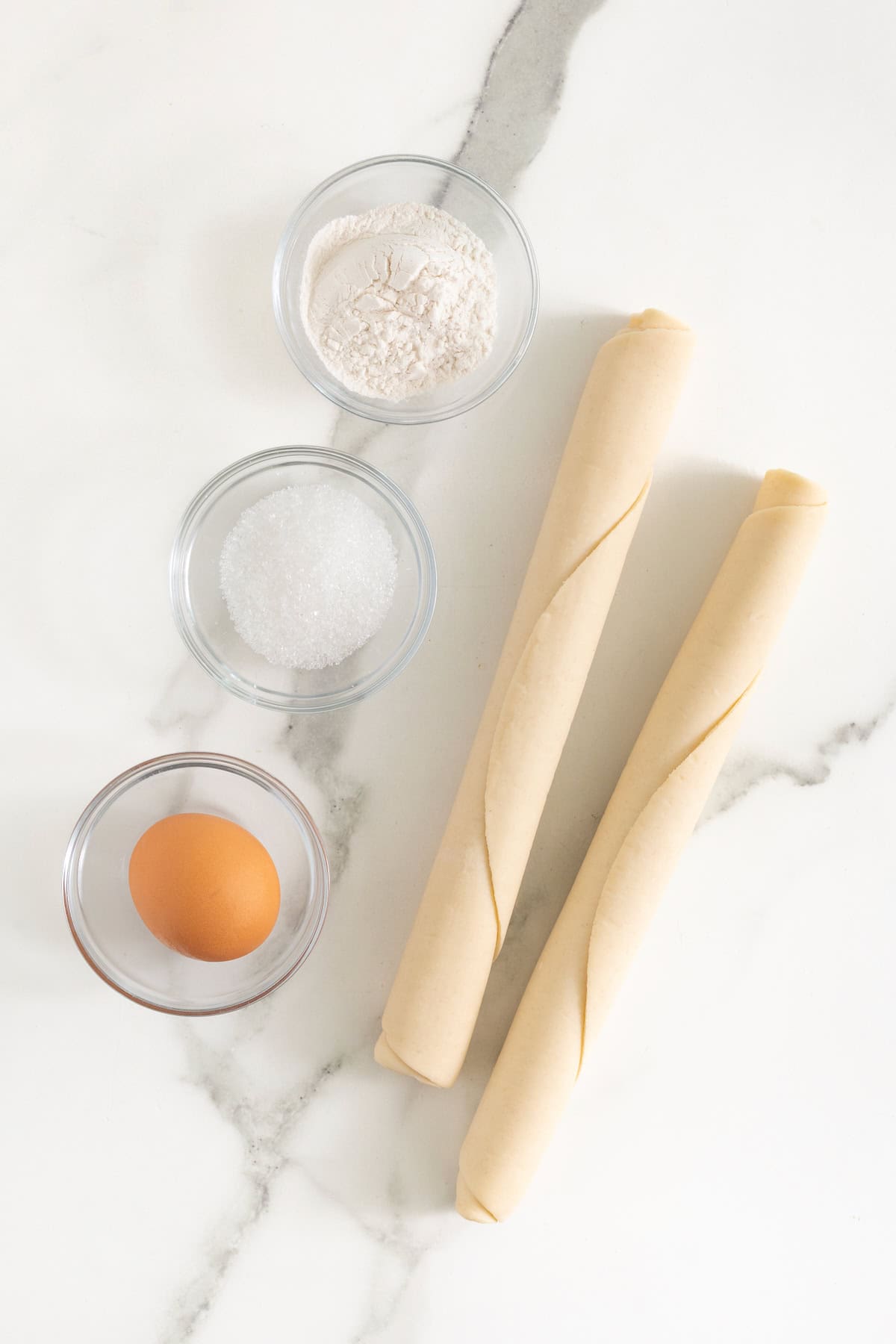 Ingredients to make lattice pie cookies on a marble counter.